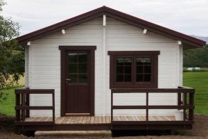 una piccola casa bianca con una porta e due panche di Heidi Cabin a Reykholt
