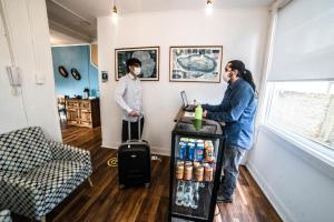 two people standing in a room with a refrigerator at HOSTAL BOUTIQUE TERRA ANTARCTICA in Punta Arenas