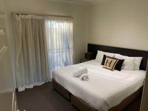 a bedroom with a large white bed with a window at H Boutique Hotel in Pokolbin
