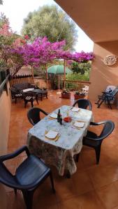 a table and chairs on a patio with purple flowers at Casa Gialla in Costa Paradiso