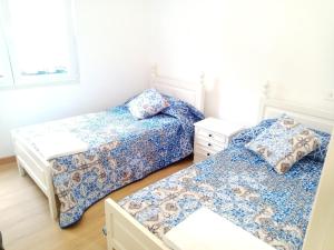2 camas en una habitación blanca con ropa de cama azul en Piso Muxía centro, en Muxía
