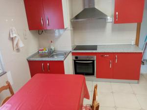una pequeña cocina con armarios rojos y una mesa roja en Piso Muxía centro, en Muxía