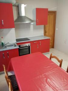 una cocina con armarios rojos y una mesa roja. en Piso Muxía centro, en Muxía