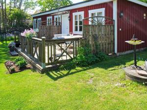 una pequeña casa roja con terraza y valla en 5 person holiday home in S LVESBORG, en Sölvesborg