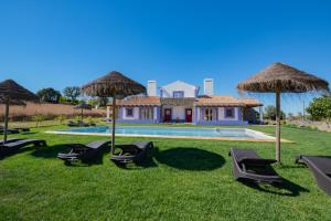 Villa con piscina con sillas y sombrillas. en Ares do Monte - Turismo Rural, en Cercal
