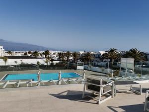 uitzicht op het zwembad vanaf het balkon van een hotel bij White Suite Deluxe in Costa Teguise