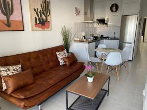 sala de estar con sofá marrón y cocina en White Suite Deluxe, en Costa Teguise