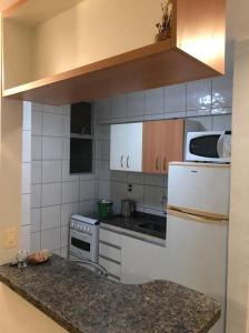 a kitchen with a white refrigerator and a microwave at Apartamento mobiliado para temporada-Rio Quente in Rio Quente