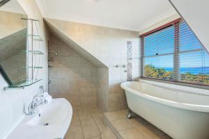 un bagno con vasca, lavandino e finestra di Whale Cove Circuit a Eden