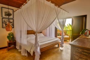 um quarto com uma cama de dossel e cortinas brancas em Hara Pousada e SPA em São Miguel do Gostoso
