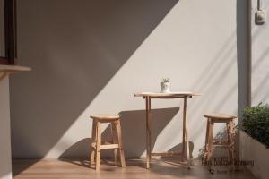 a table and two stools in front of a wall at Petra Boutique Donmuang in Bangkok