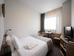 長野市にある長野東急REIホテルのベッドとテレビが備わるホテルルームです。