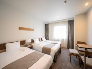 um quarto de hotel com duas camas e uma mesa em Nagano Tokyu REI Hotel em Nagano