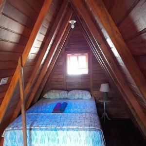 a bed in a wooden cabin with a window at CHALÉ HAKUNA MATATA-Vale do capão in Vale do Capao