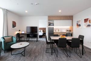 a living room with a table and chairs and a kitchen at Quest Takapuna in Auckland