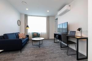 a living room with a couch and a desk with a laptop at Quest Takapuna in Auckland