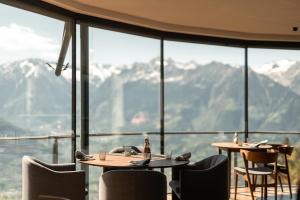 a restaurant with tables and chairs and a view of mountains at Miramonti Boutique Hotel in Avelengo