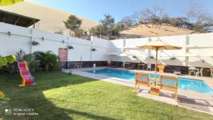 a hotel with a swimming pool and an umbrella at Hotel Santa Maria in Ica