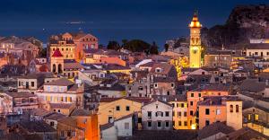 a city with a clock tower and a town at night at GEORGES IPSOS APARTMENTS in Ipsos