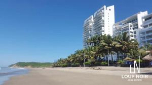 - une vue sur une plage bordée de palmiers et de bâtiments dans l'établissement Departamento vista al mar 2D, à Tonsupa