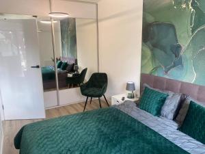 1 dormitorio con cama verde y espejo en Apartament Sosnowa 4, en Mielno