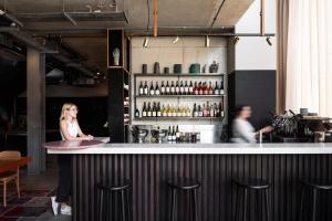 a woman standing at a bar in a restaurant at Alex Hotel in Perth