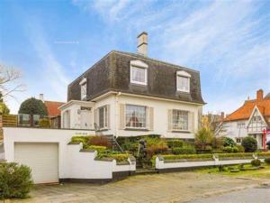 ein weißes Haus mit schwarzem Dach und einer Garage in der Unterkunft Villa Elsjes Droom in Koksijde