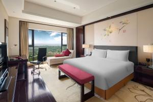 a bedroom with a large white bed and a living room at Crowne Plaza Chengdu Panda Garden, an IHG Hotel in Chengdu