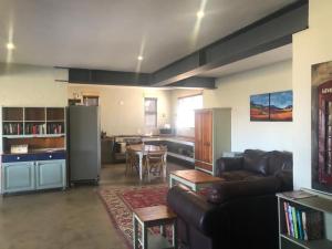 a living room with a black couch and a kitchen at The Oaktree House in Clarens