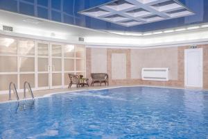 a large pool in a room with chairs and a table at Baltic Star Hotel in Petergof