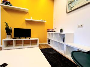 uma sala de estar com televisão numa parede amarela em RailWay Bed HOSTEL em Kaunas