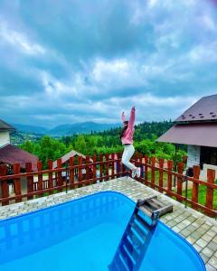 a woman jumping in the air over a swimming pool at Біля лісу Шале з двома спальнями in Slavske