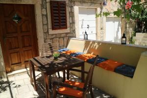 a wooden table and chairs on a balcony with a table and a couch at Studio Apartments & Rooms Lela in Šipanska Luka