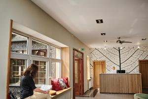 a woman sitting on a bench in a room at Park Hotel in Świdnica