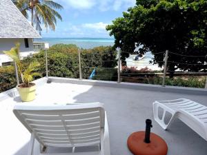 a patio with white chairs and a view of the ocean at Villa Ximun in Roches Noires