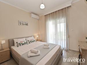 a bedroom with a large bed with towels on it at Villa Iris by RentalsPro - Agios Mamas Beach in Agios Mamas