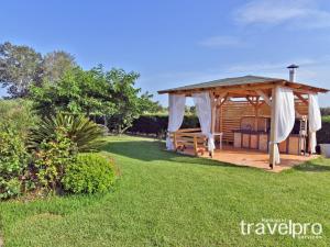 einen hölzernen Pavillon in einem Garten mit grünem Gras in der Unterkunft Villa Iris by RentalsPro - Agios Mamas Beach in Agios Mamas