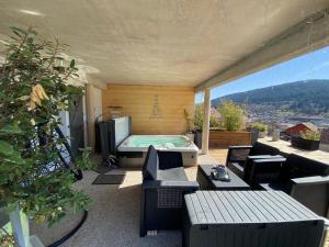 a patio with a jacuzzi tub on a balcony at AU NID COSY D'ISA A GERARDMER VOSGES - Spas privatifs in Gérardmer