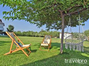 2 Stühle und eine Schaukel unter einem Baum in der Unterkunft Villa Iris by RentalsPro - Agios Mamas Beach in Agios Mamas