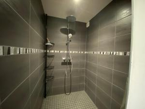a shower in a bathroom with gray tiles at AU NID COSY D'ISA A GERARDMER VOSGES - Spas privatifs in Gérardmer +30 photos