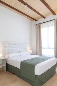 a bedroom with a large white bed with a green blanket at Ad Hoc Vitae Retreats & Health Only Adults in Beniarbeig