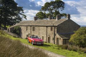 a red car parked in front of a stone house at Higher Scarcliffe at Broughton Sanctuary in Skipton
