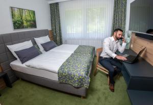 a man talking on a cell phone in a hotel room at Waldhotel Ehrental in Schmalkalden