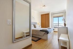 um espelho num quarto com uma cama e uma janela em Villa Rosa Apartment em Portimão