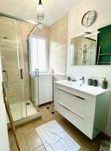 a bathroom with a sink and a shower and a clock at Saturne YourHostHelper in Caen