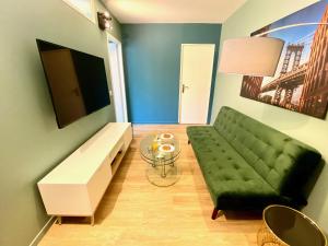 a living room with a green couch and a glass table at Saturne YourHostHelper in Caen
