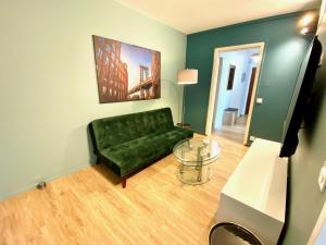 a living room with a green couch and a glass table at Saturne YourHostHelper in Caen