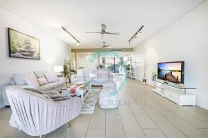 sala de estar con muebles blancos y TV de pantalla plana en ZEN PENINSULA - Darwin's Prestigious WaterFront Retreat en Darwin