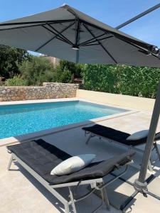 an umbrella and a lounge chair next to a swimming pool at Ferienhaus Marija mit Pool in Vilanija