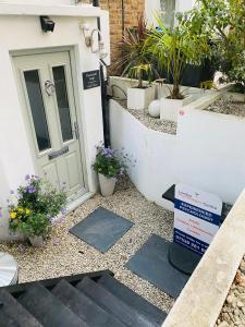 una señal de bienvenida frente a una puerta con macetas en Stunning, peaceful entire flat in the centre of Wimbledon, en Londres